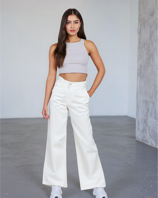 Woman wearing a gray tank top and white pants in a minimalistic setting