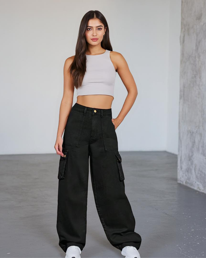 Woman wearing a light gray crop top and black cargo pants in a minimalistic setting.